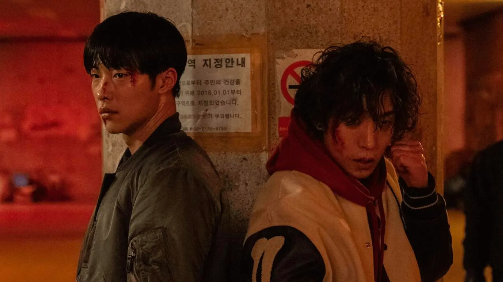 Two bloodied men standing side by side after a fight, looking ahead